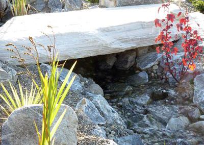 Large slab rock creating bridge over flowing creek.